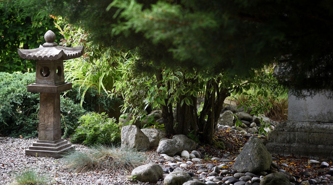 Japanese stone zen snow lantern (ishi doro) amongst rocks and stone in an English garden