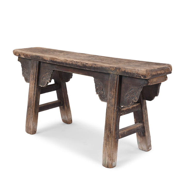 Angled View Of 19th Century Elm Spring Bench From Shanxi With Hand Carved Cloud Motifs And Splayed Legs | Indigo Antiques