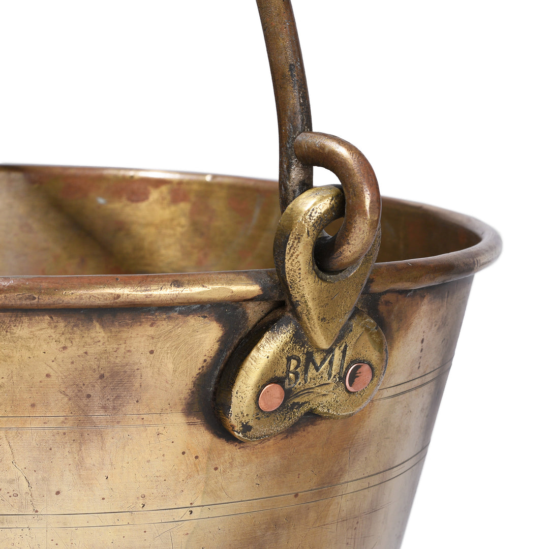 Close-up of a brass bucket with a handle and visible Bombay Municipality branding