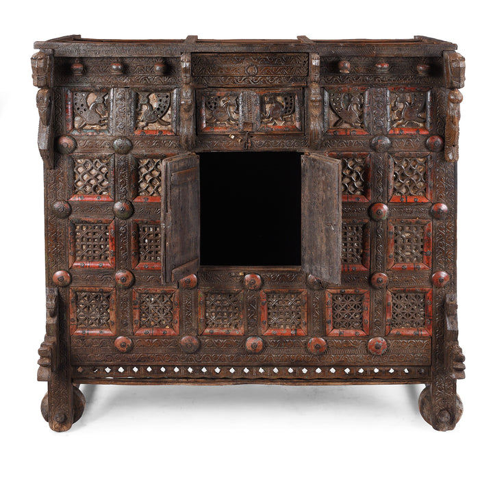 Open Doors View Of Antique 19th-century Indian dowry chest from Gujarat with intricate animal carvings, geometric patterns, and hidden compartments, set on wheels.
