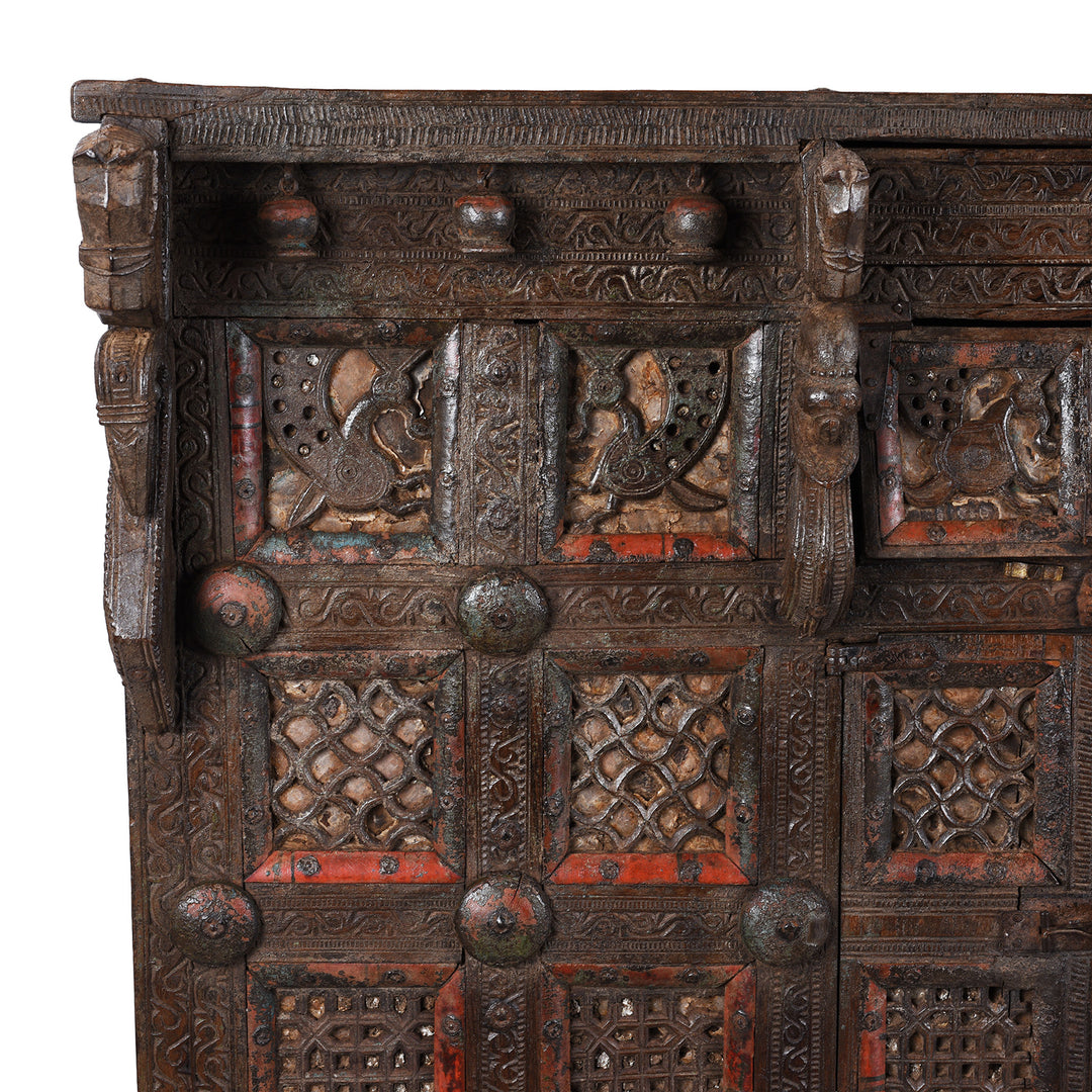 Corner Detail Displaying Peacock Carvings On Antique 19th-century Indian dowry chest from Gujarat with intricate animal carvings, geometric patterns, and hidden compartments, set on wheels.