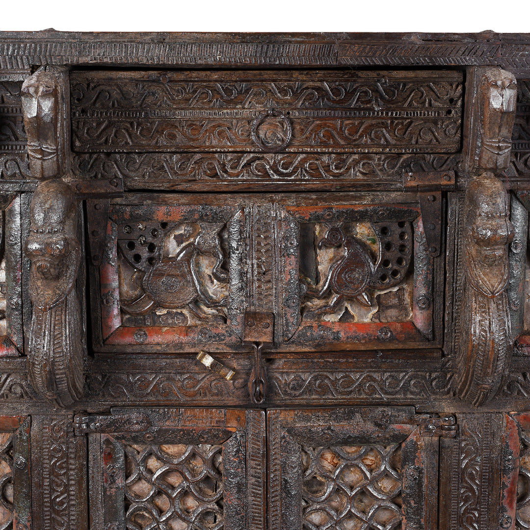 Central Panel Peacock Carvings From Antique 19th-century Indian dowry chest from Gujarat with intricate animal carvings, geometric patterns, and hidden compartments, set on wheels.