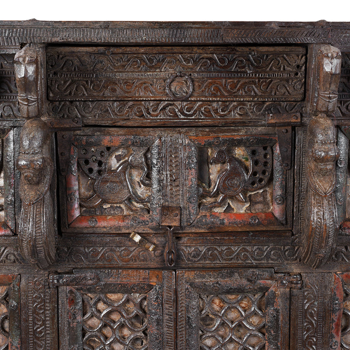 Central Panel Peacock Carvings From Antique 19th-century Indian dowry chest from Gujarat with intricate animal carvings, geometric patterns, and hidden compartments, set on wheels.
