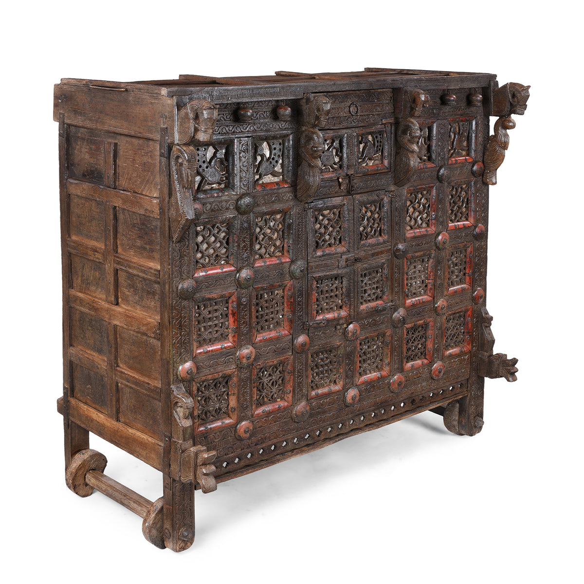 Angled VIew Of Antique 19th-century Indian dowry chest from Gujarat with intricate animal carvings, geometric patterns, and hidden compartments, set on wheels.