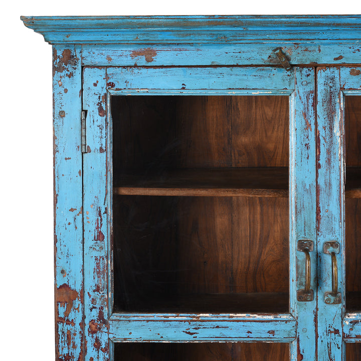 Corner Detail Showing Distressed Paintwork On Antique Indian Teak Book Cabinet With Distressed Blue Frame, Warm Teak Interior, Five Shelves, And Sliding Central Panels