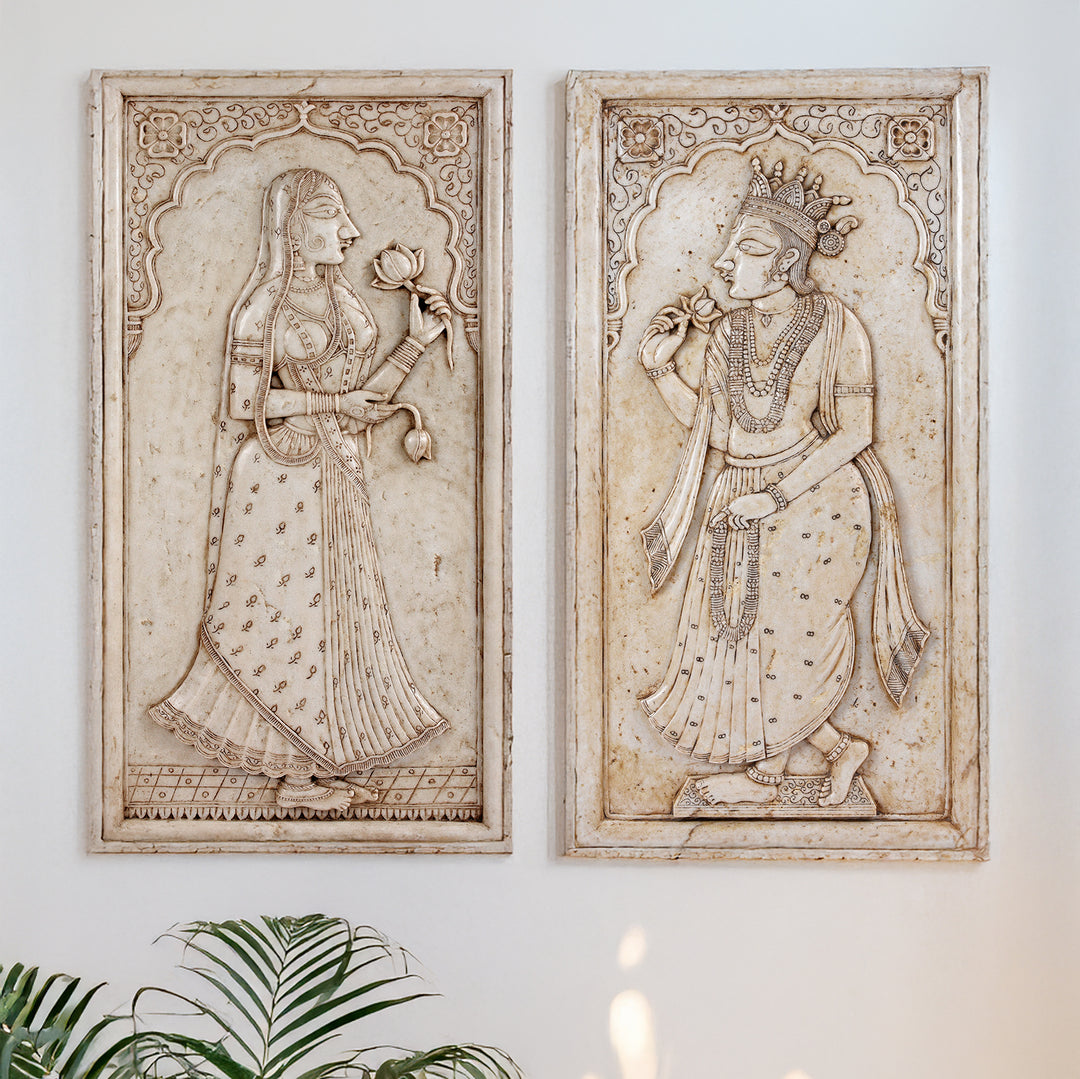 Two decorative panels with intricate carvings of a Maharani and a Maharaja on a marble background