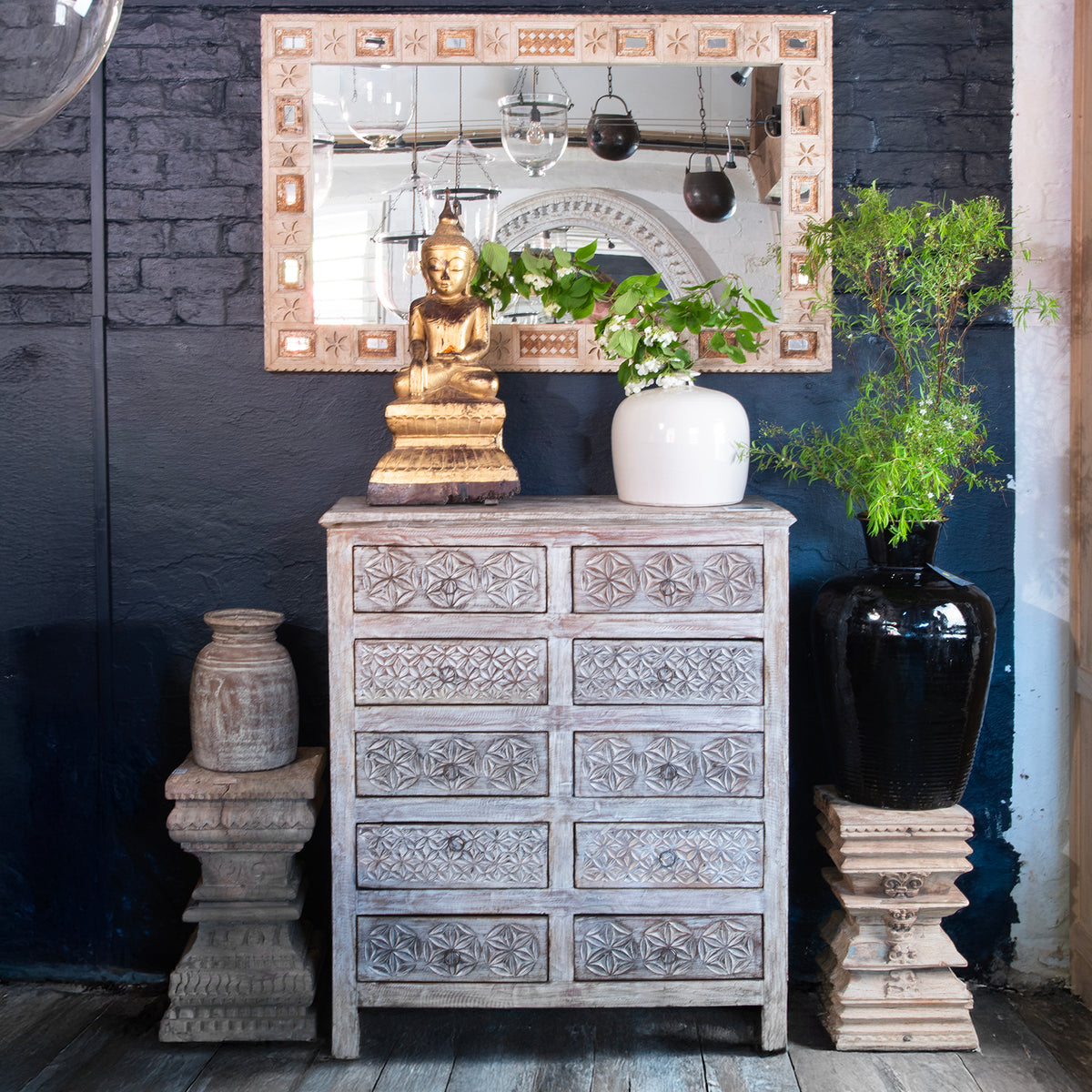 Rustic wood chest of drawers with geometric designs and a Burmese Buddha