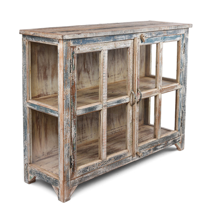 Angled View Of Glazed Display Cabinet With Distressed Finish, Reclaimed South Indian Teak, Two Doors, And Painted Interior With Shelf