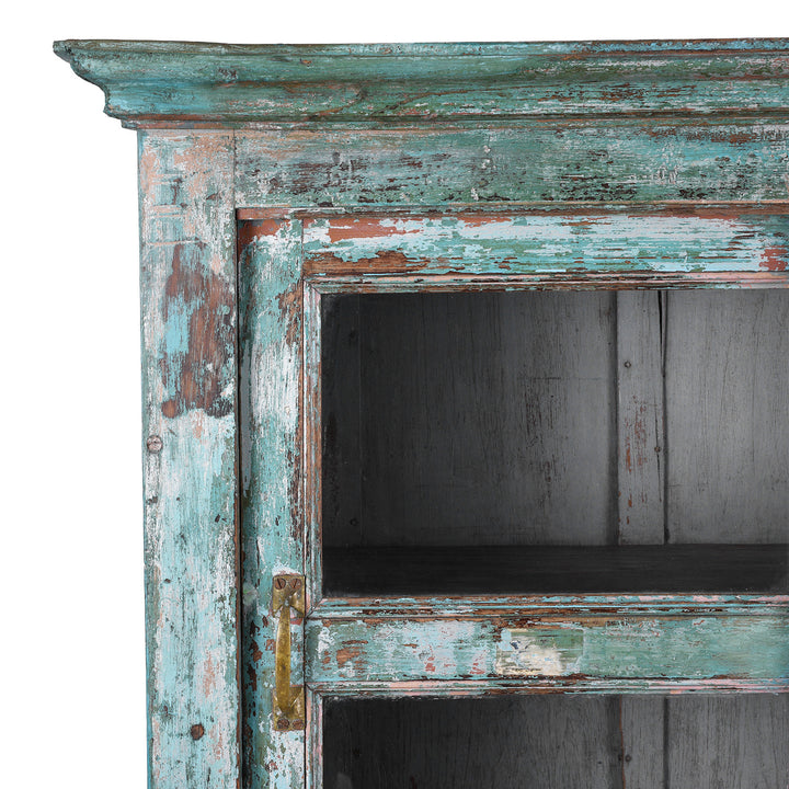 Corner Detail SHowing Faded Paintwork On Green painted Indian teak glazed cabinet circa 1920 with four sliding glass panels, three fixed shelves and distressed original paint | Indigo Antiques