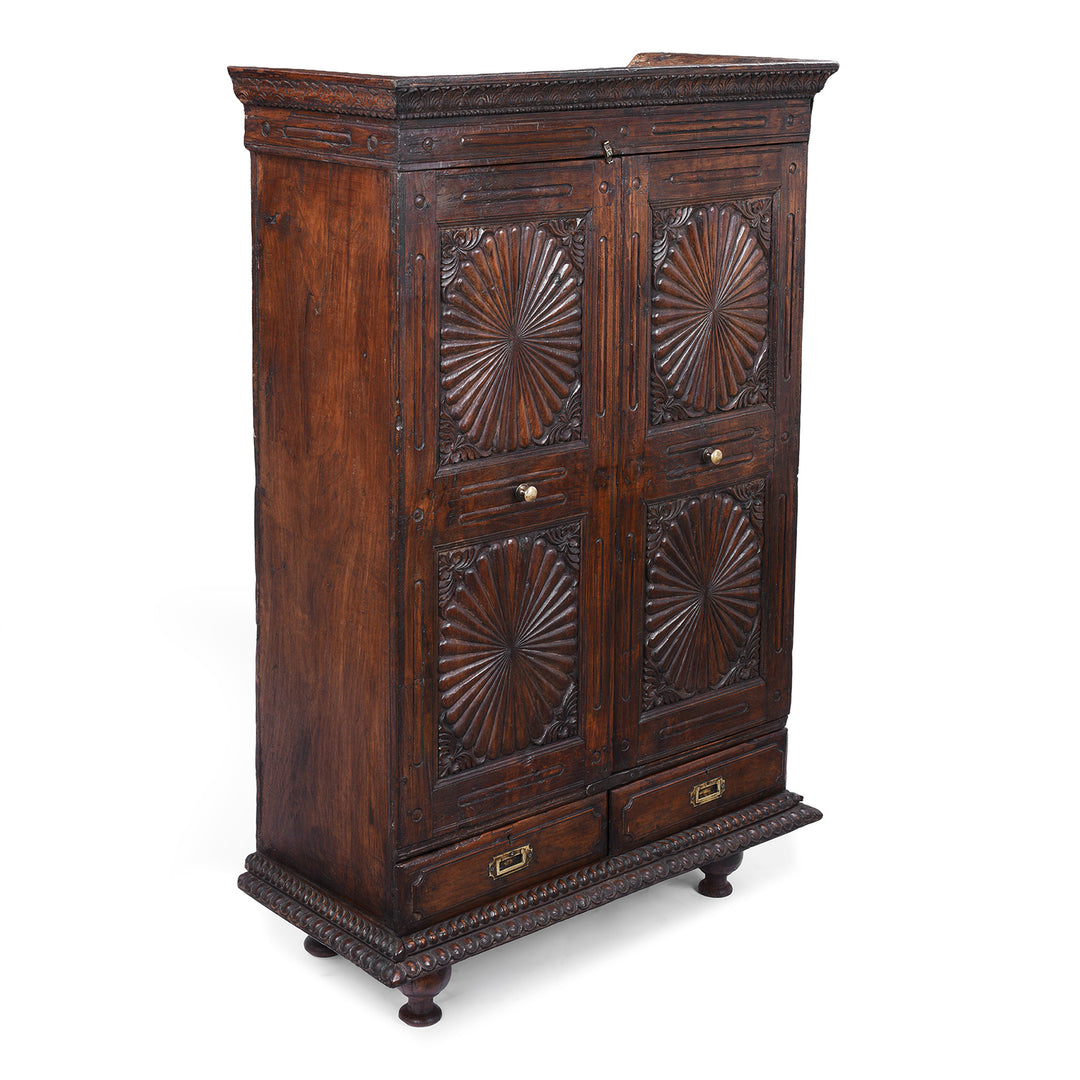 Angled View Of 19th Century Indian Teak Almirah Cabinet With Deeply Carved Sunburst Panels And Indo Portuguese Influence