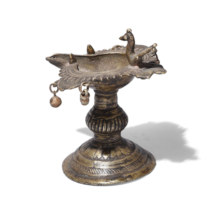 Rear View Of Circa 1920 Dhokra Brass Oil Lamp From Chhattisgarh With Peacock Finial And Suspended Bell Ornaments Cast Using Lost Wax Technique