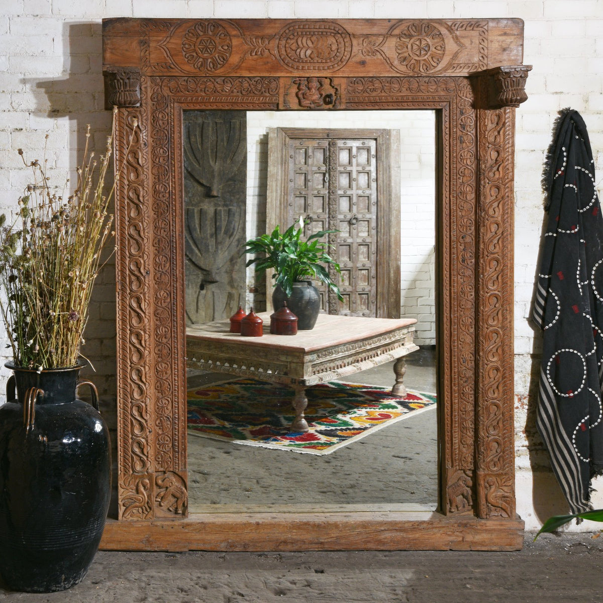 Antique Indian interior with an old takhat coffee table from Gujarat shown through a door frame mirror from Andhra Pradesh | Indigo Antiques