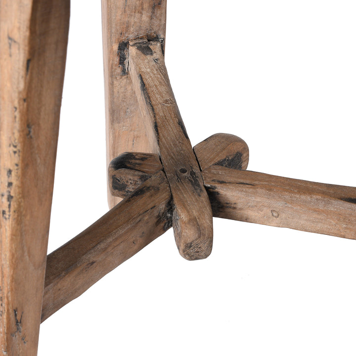 Close-up of a rustic wooden stool with intersecting beams on a white background