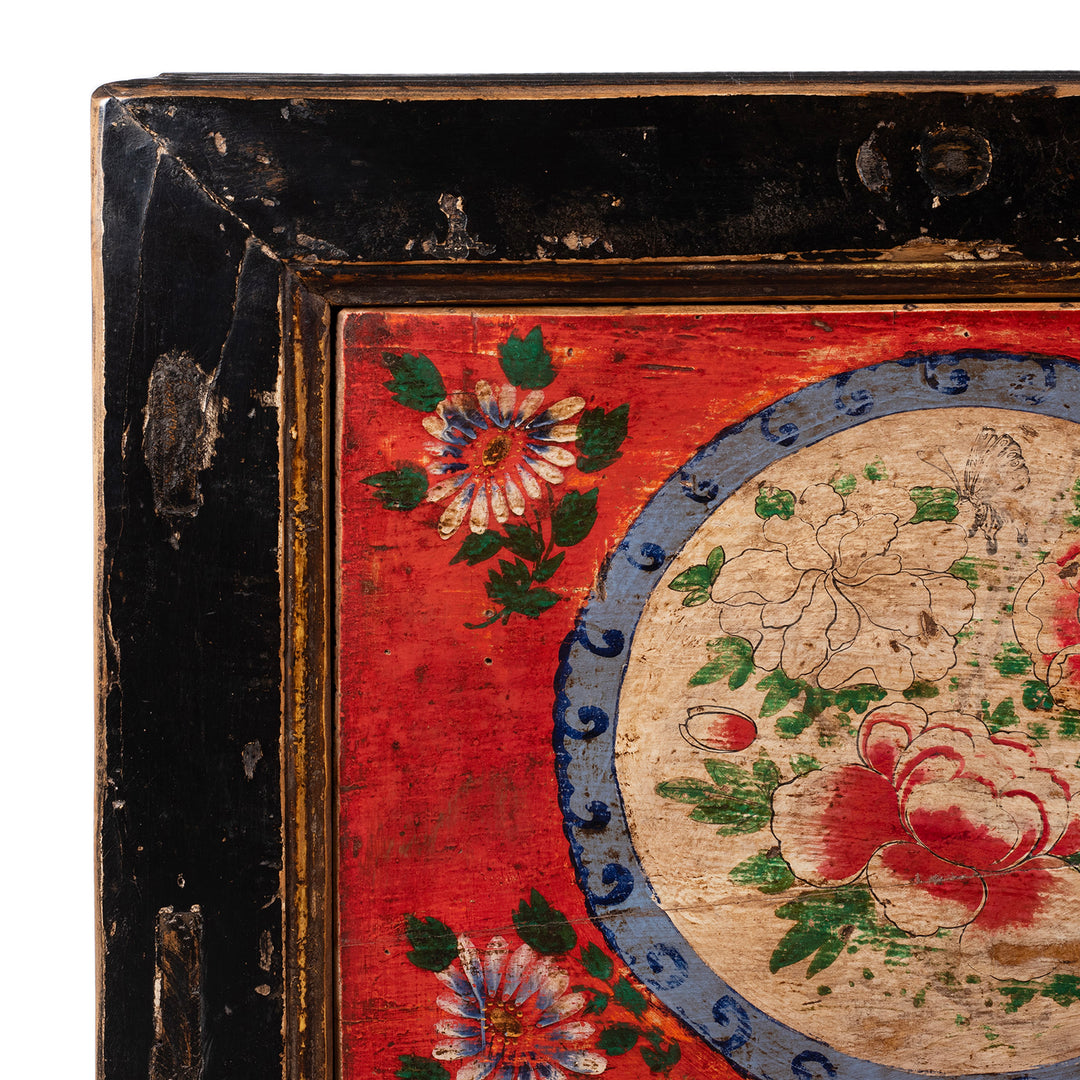 Decorative panel with floral patterns on a red background, showing signs of wear.