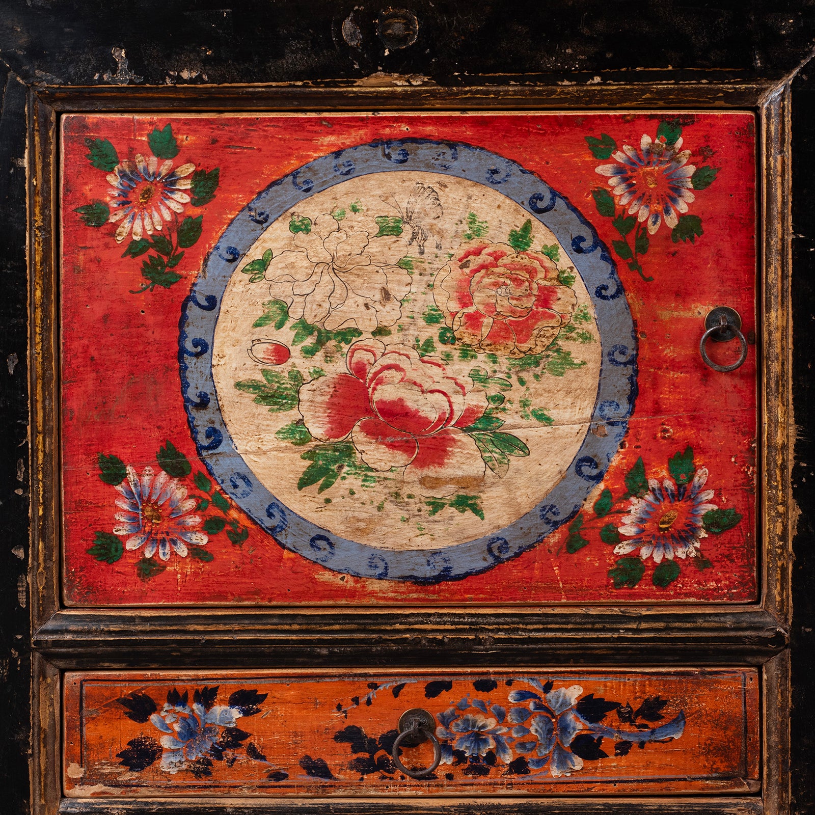 Vivid vivid red and orange panels and intricate peony and chrysanthemum motifs symbolising prosperity and longevity on an antique Mongolian cabinet