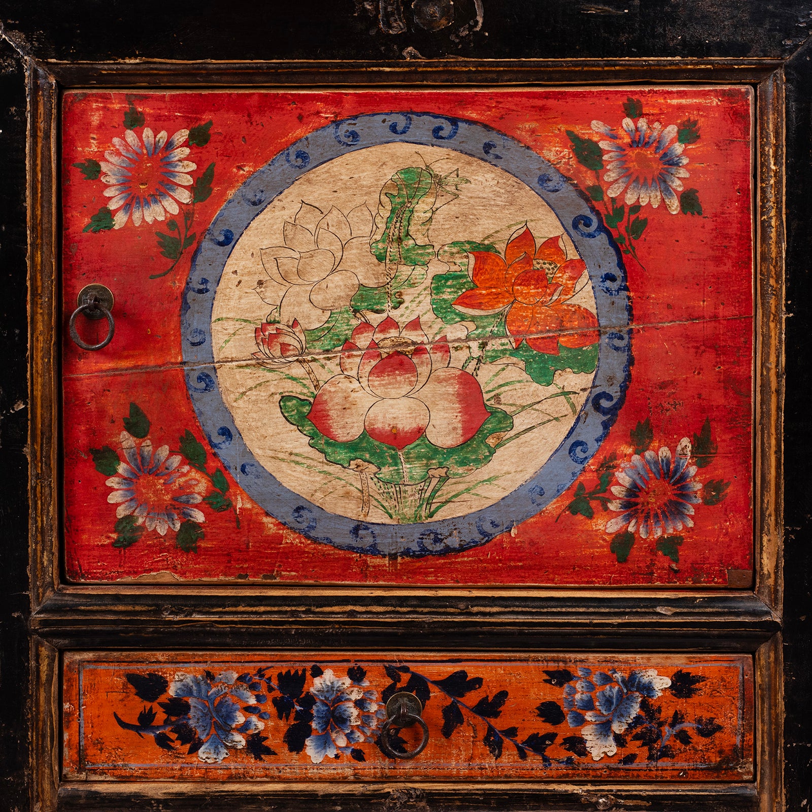 Vivid vivid red and orange panels and intricate peony and chrysanthemum motifs symbolising prosperity and longevity on an antique Mongolian cabinet
