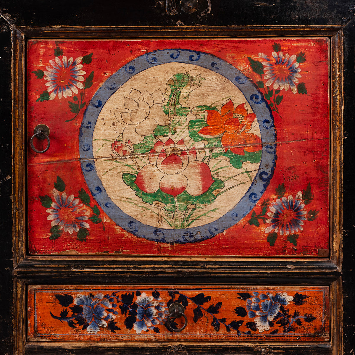 Vivid vivid red and orange panels and intricate peony and chrysanthemum motifs symbolising prosperity and longevity on an antique Mongolian cabinet