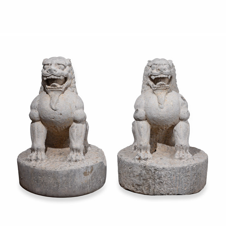 Pair Of Carved Stone Chinese Guardian Lions With Stylised Manes Seated On Circular Plinths
