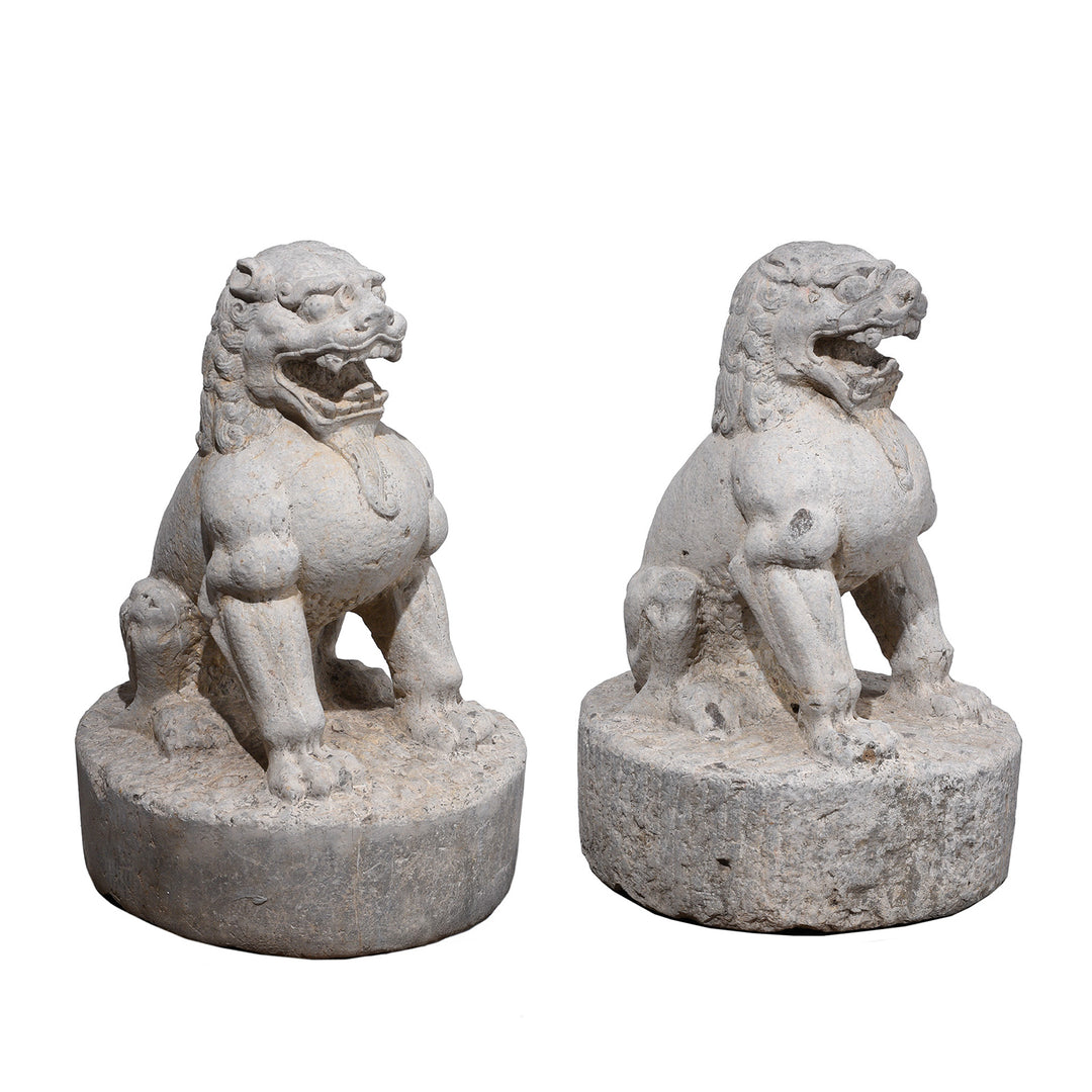Pair Of Carved Stone Chinese Guardian Lions With Stylised Manes Seated On Circular Plinths