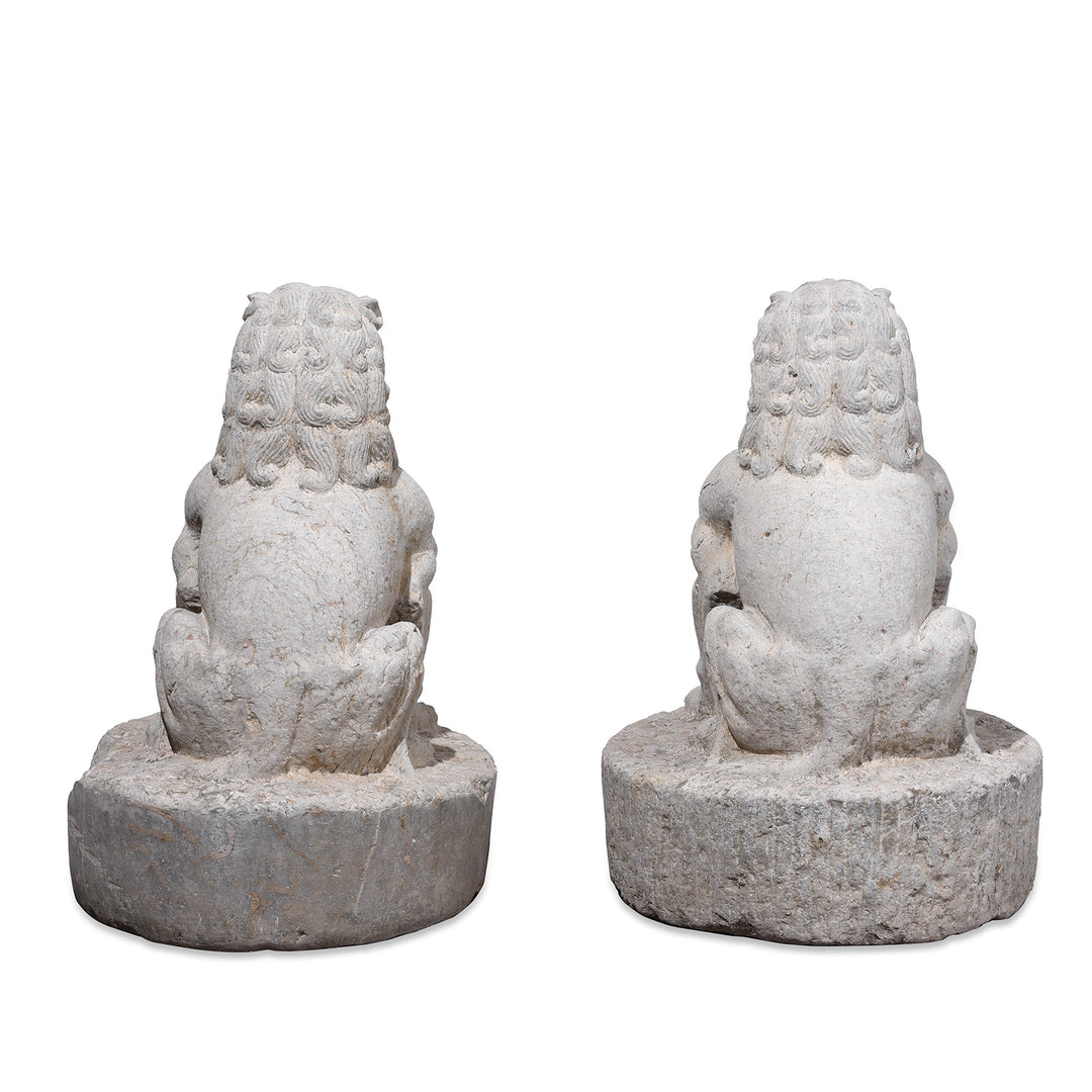 Rear View Of Pair Of Carved Stone Chinese Guardian Lions With Stylised Manes Seated On Circular Plinths