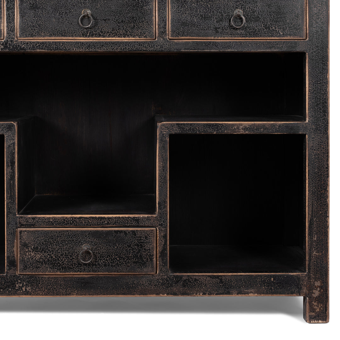 Bottom Corner Detail From Tall Black Distressed Pine Shelf Unit With Geometric Open Compartments And Drawers