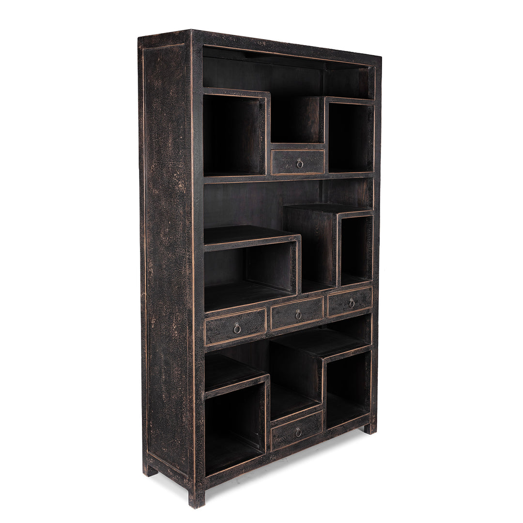 Angled View Of Tall Black Distressed Pine Shelf Unit With Geometric Open Compartments And Drawers