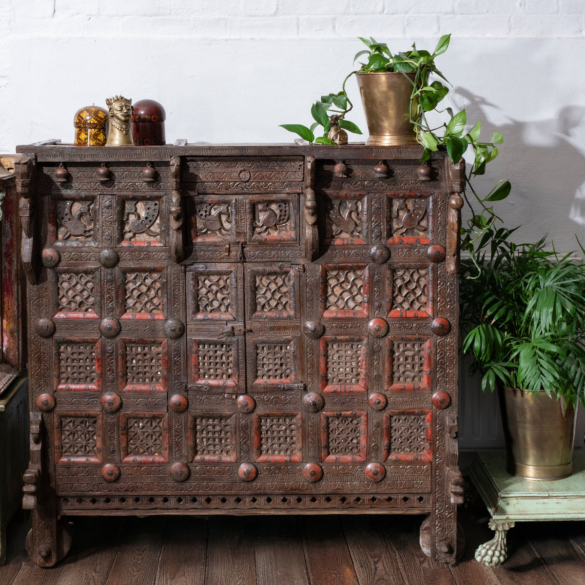 Antique 19th-century Indian dowry chest from Gujarat with intricate animal carvings, geometric patterns, and hidden compartments, set on wheels.