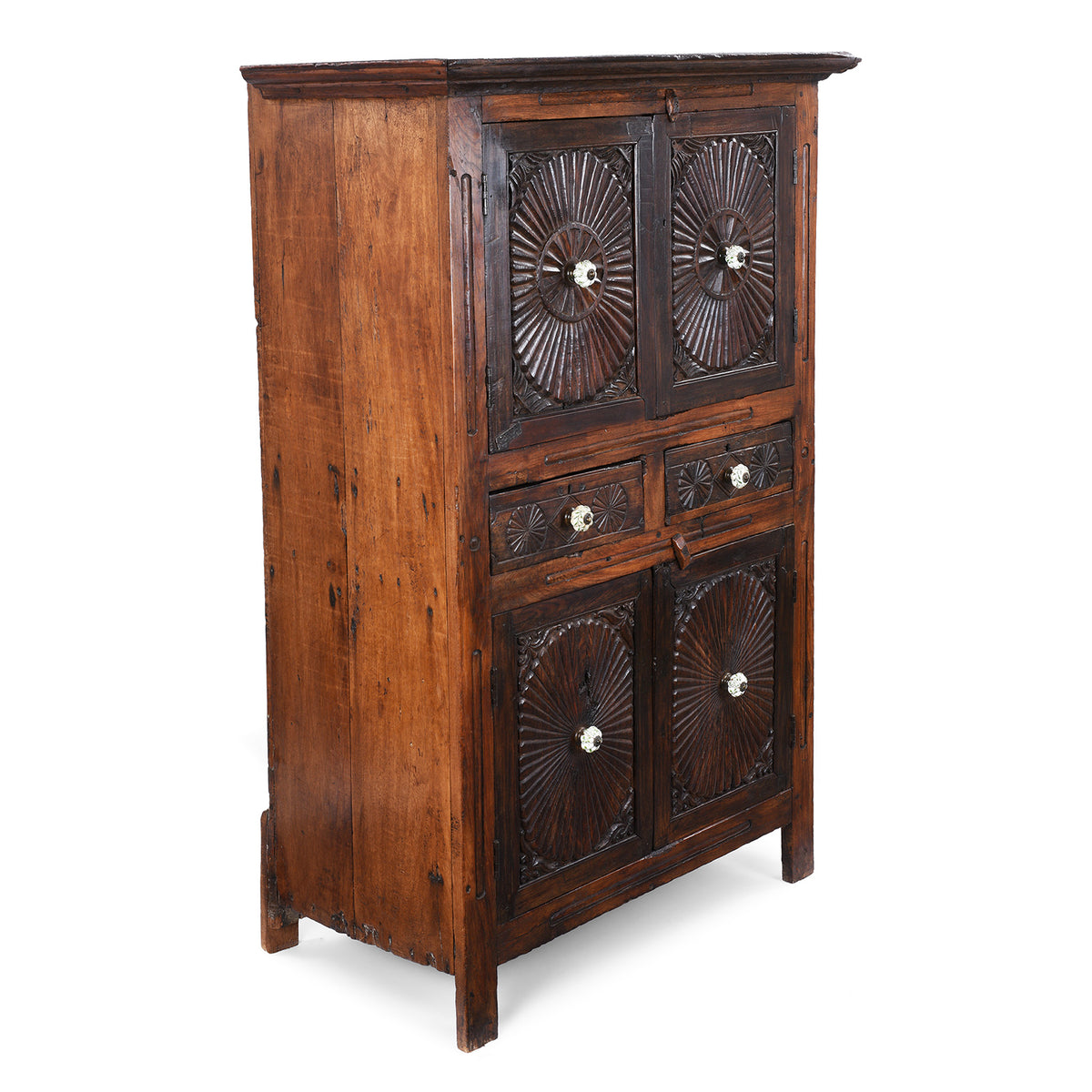 Angled View Of Indian Teak Almirah Cabinet With Hand-Carved Sunburst Panels, Two Drawers And White Ceramic Handles