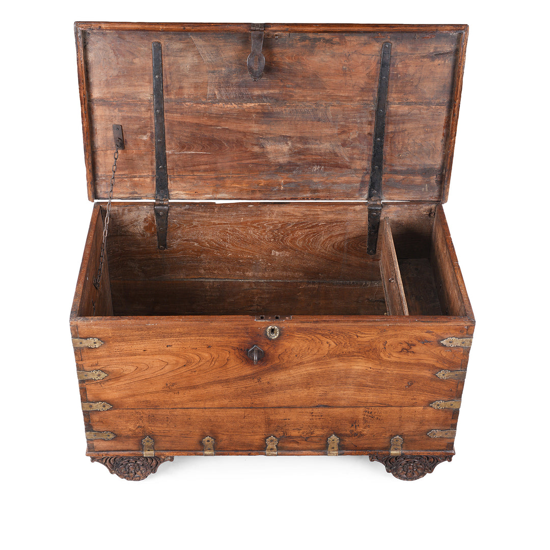 P[em View Of Antique mid-19th century teak chest from Gujarat with hidden wheels, carved floral feet, and original iron fittings.