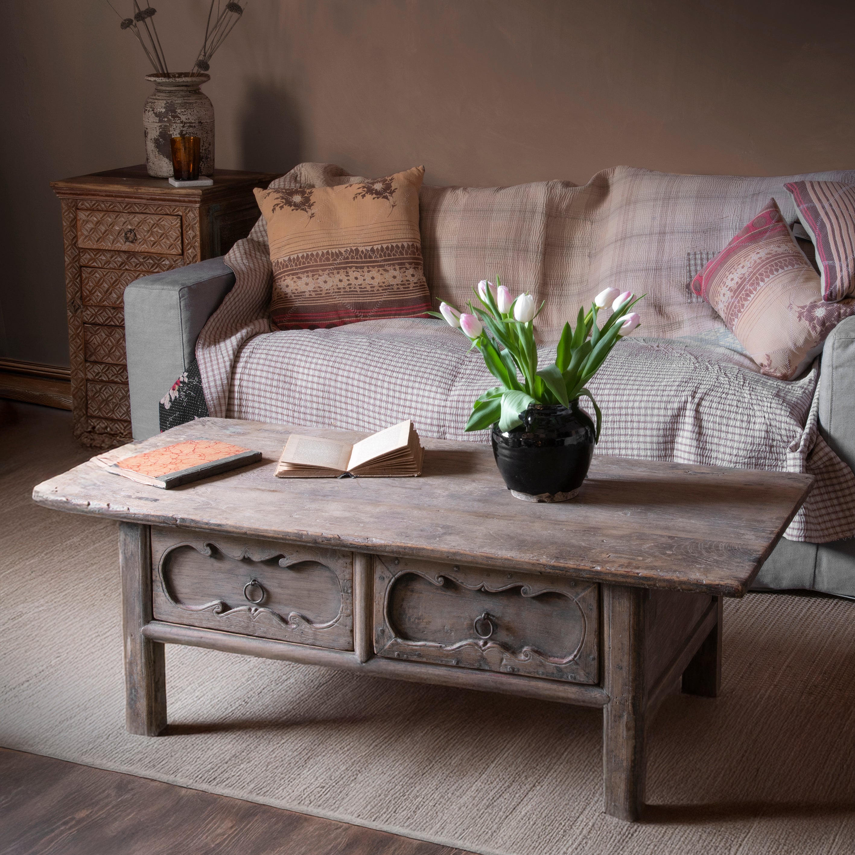 An antique coffee table with vase of flowers