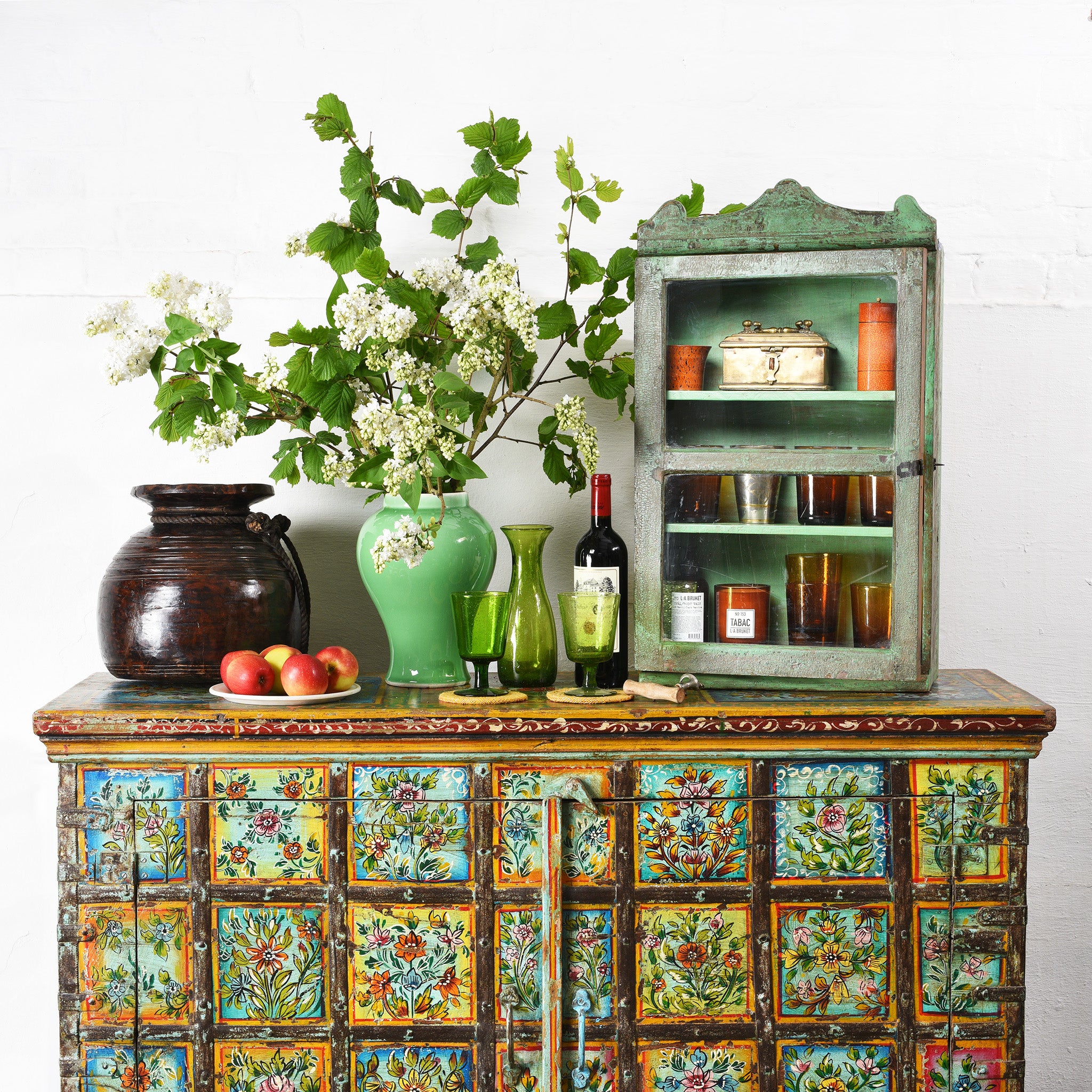 A painted sideboard with a vase and glassware on top